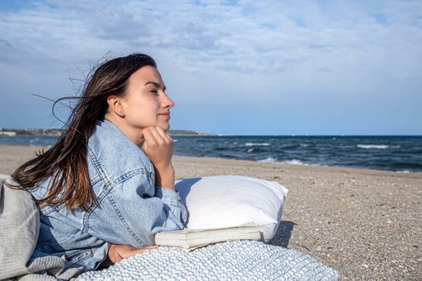 Junge Frau liegt mit Reisekissen am Strand und genießt ihr Outdoorabendteuer